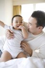 Chinese hält Säugling auf Bett — Stockfoto