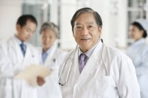 Китайська, робоче місце лікаря стоїть в лікарні з колегами у фоновому режимі — стокове фото