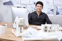 Arquiteto chinês sentado no escritório e sorrindo — Fotografia de Stock