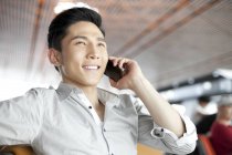 Китаец разговаривает по телефону в здании аэропорта — стоковое фото