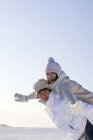 Chino pareja hombre holding mujer piggyback en estación de esquí - foto de stock