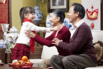 Grandparents embracing granddaughter during Chinese New Year — Stock Photo