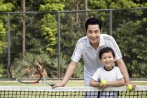 Китайский отец и сын позируют на теннисном корте — стоковое фото