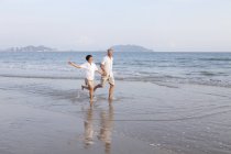 Senior Cinese coppia in esecuzione in spiaggia — Foto stock