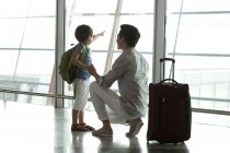 Padre e hijo chinos señalando a la vista en el aeropuerto - foto de stock
