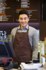 Продавец в китайском кафе, стоящий за стойкой с кассой — стоковое фото