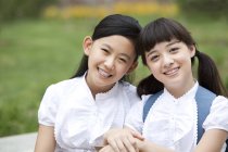 Школьные девочки в школьной форме сидят бок о бок — стоковое фото