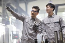 Chinese engineers working with machine parts at factory — Stock Photo