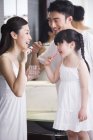 Китайские родители с дочерью чистят зубы в ванной комнате — стоковое фото