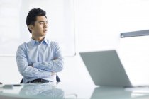 Hombre de negocios chino pensando en escritorio en la oficina - foto de stock