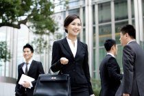 Chinese businesswoman holding briefcase on street with businessmen — Stock Photo
