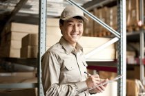 Chinese warehouse worker with clipboard — Stock Photo