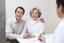 Coppia di anziani cinesi seduto con il medico in ospedale — Foto stock