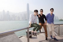 Giovani uomini cinesi seduti sulla balaustra a Victoria Harbor, Hong Kong — Foto stock