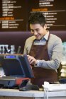 Homme chinois commis de café travaillant à la caisse enregistreuse — Photo de stock