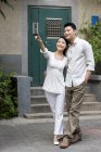 Chinese couple embracing on street at pointing at view — Stock Photo