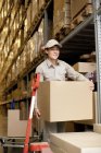 Chinese warehouse worker carrying cardboard boxes — Stock Photo