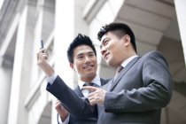 Китайские коллеги по бизнесу используют смартфон на улице — стоковое фото