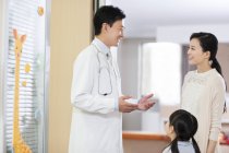 Médico chino hablando con la chica madre en el hospital - foto de stock