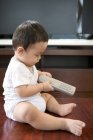 Chinese baby boy holding remote control — Stock Photo