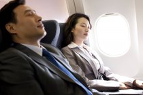 Chinese business people resting on flight — Stock Photo