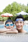 Chinese father and son in swimming goggles at pool — Stock Photo