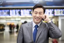 Китайский бизнесмен разговаривает по телефону в аэропорту — стоковое фото