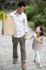 Chinese father and daughter walking on street with groceries — Stock Photo