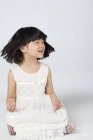 Маленькая китаянка качает головой в позе лотоса на сером фоне — стоковое фото