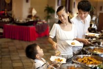 Mère chinoise aidant son fils au buffet de l'hôtel — Photo de stock