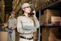 Male and female Chinese manual workers with walkie-talkie in warehouse — Stock Photo