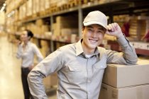 Chinese warehouse worker with businesswoman in background — Stock Photo
