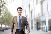 Confident Chinese businessman walking in city downtown — Stock Photo
