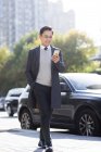 Chinese businessman using smartphone by city road — Stock Photo
