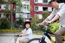Chinese father and son riding bicycles in residential district — Stock Photo