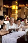 Famille chinoise multi-génération regardant à travers le menu dans le restaurant — Photo de stock