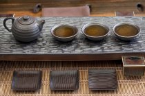 Chinese teapot and tea cups with drink in a row — Stock Photo