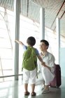 Chinese father and son pointing at view at airport — Stock Photo