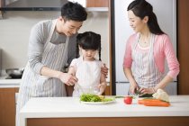 Chinese family with daughter cooking salad in kitchen — Stock Photo