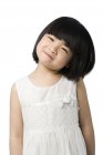 Portrait of a little Chinese girl tilting head on white background — Stock Photo