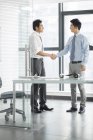 Young Chinese businessmen shaking hands in office — Stock Photo