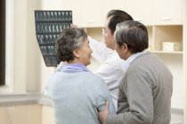 Médico chino mostrando resultado de la prueba de rayos X a pareja mayor - foto de stock