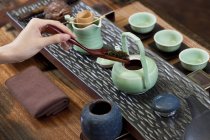 Primer plano de la mano femenina poniendo hojas de té en la tetera - foto de stock