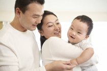 Padres chinos sosteniendo bebé hijo - foto de stock