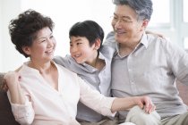 Chinese grandson embracing cheerful grandparents — Stock Photo