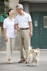 Casal chinês sênior andando com cão na rua — Fotografia de Stock