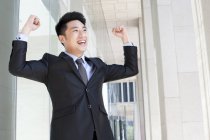 Empresario chino animando con los brazos levantados - foto de stock