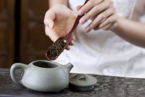 Close-up de mãos femininas colocando folhas de chá em bule — Fotografia de Stock