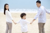 Китайская семья оглядывается назад рука об руку на пляже — стоковое фото