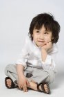 Portrait d'un petit garçon asiatique avec la main sur le menton sur fond gris — Photo de stock